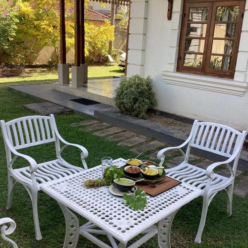two white chairs and a table with food on it at Headman House Antique Villa - Ahangama in Ahangama