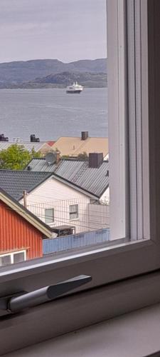 a window with a view of a boat in the water at Palmehagen in Kirkenes