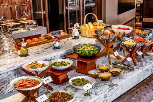 ein Buffet mit vielen Schüsseln Essen auf dem Tisch in der Unterkunft Guangzhou Elegant International Hotel Panyu Square Metro Station Branch - Free Shuttle Bus to Canton Fair Complex During Canton Fair Period & Free Deliver Service to Guangzhou Baiyun International Airport in Guangzhou