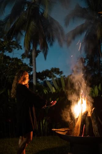 a woman standing in front of a fire at Desa Cabins in Balian