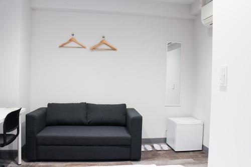 a black couch in a room with a white wall at ホステルエリーラ神田 HOSTEL EstLiLas KANDA in Tokyo