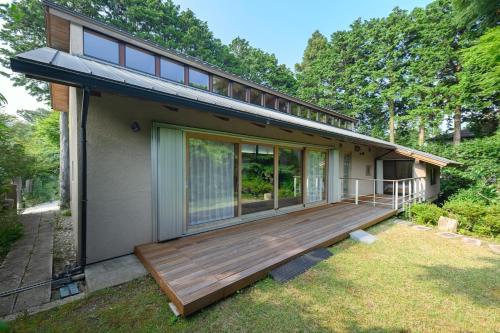 a house with a large wooden deck in the yard at 箱根こもれび庵 in Hakone