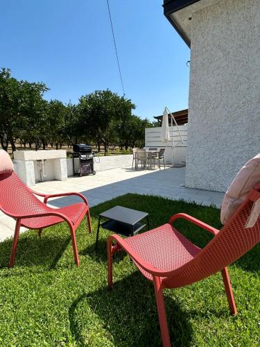 two red chairs and a table in the grass at Villa Gisa in Calalunga-Pietragrande