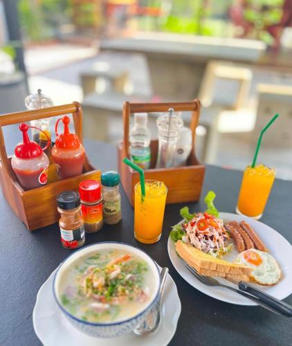a table with a plate of food and a sandwich and drinks at บ้านพักชายคลอง @บางปู สามร้อยยอด in Ban Bang Pu