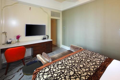 a hotel room with a bed and a desk with a television at Jin Jiang Hotel Shanghai - historical hotel in the city-center of Huaihai shopping area and convenient access to metro lines in Shanghai