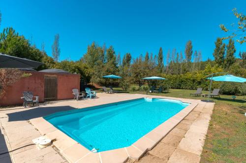 a swimming pool in a yard with umbrellas at Domaine Plan Des Devens Tendresse in Roussillon