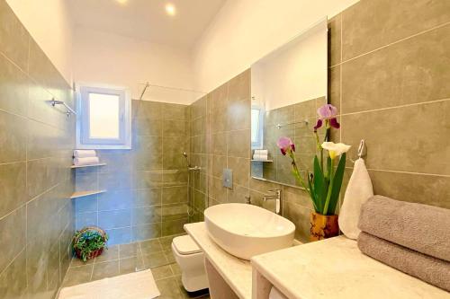a bathroom with a toilet and a sink with flowers at NISSAKI SUNLIGHT by Sealand Villas in Nisakion