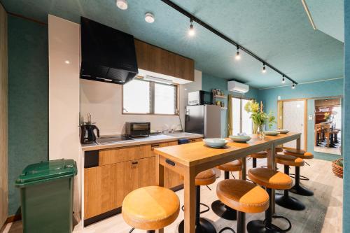 a kitchen with a wooden table and stools in it at Tokyo Manga Stay 駅1分貸切で85平米 日本の有名マンガが読める宿 9名までOK in Tokyo