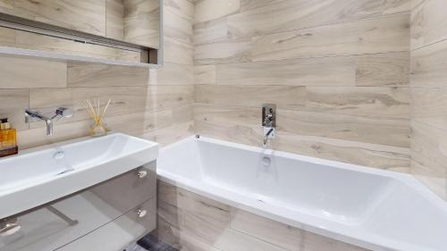 a bathroom with a white tub and a sink at Panorama Penthouse in Ashford