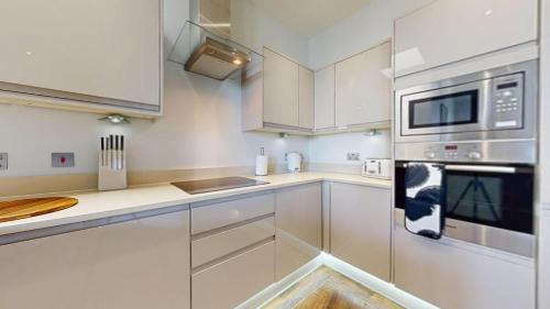 a kitchen with white cabinets and stainless steel appliances at Panorama Penthouse in Ashford
