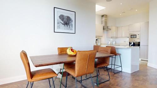 a kitchen and dining room with a wooden table and chairs at Panorama Penthouse in Ashford