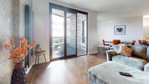 a living room with a couch and a glass door at Panorama Penthouse in Ashford