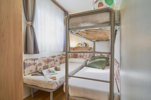 ein Etagenbett mit einer Couch und einem Stuhl in einem Zimmer in der Unterkunft Feriendorf Oasi Mobilehome Maui für 5 Personen in Sottomarina