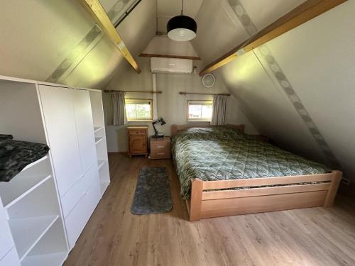 une chambre avec un lit dans un grenier dans l'établissement Recreational cottage with lots of privacy, large forest garden!, à IJhorst