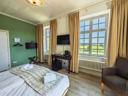 a bedroom with a bed and a chair and windows at Kasteel Pietersheim Maastricht - Lanaken in Lanaken