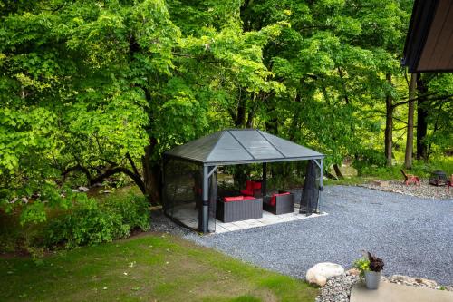 a black gazebo with red chairs in it at By the river - Le 91 in Frelighsburg