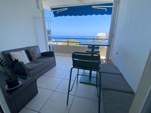 a balcony with a table and a couch and the ocean at Appart sympa, vue sur le lagon à Saint-Gilles les bains in Saint-Gilles les Bains