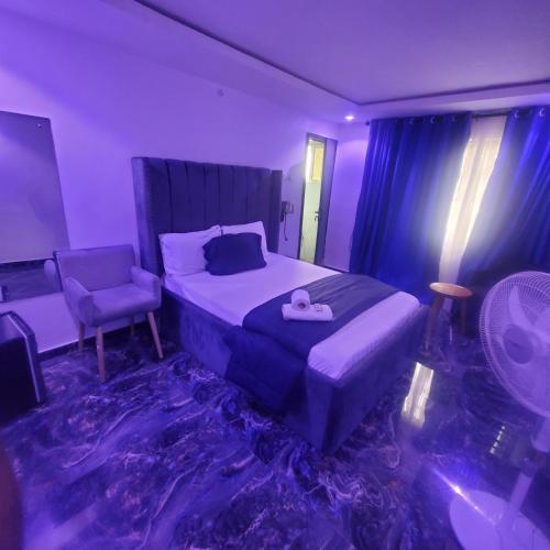 a bedroom with a purple room with a bed and a chair at WELTONS Apartment BABA YUSUF in Ikeja