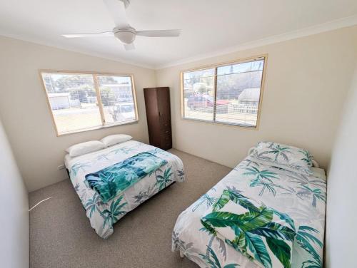 a bedroom with two beds and two windows at Aqua Sands Chalets in Lancelin