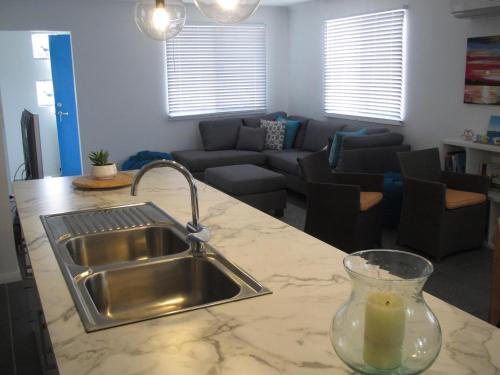 a kitchen counter with a sink and a living room at Seagulls in Lancelin