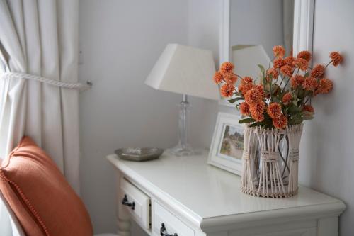 a vase of orange flowers on a table with a lamp at Rowan Cottage-Ebrington in Ebrington