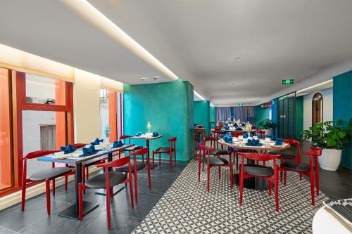 a restaurant with tables and red chairs and blue walls at Le Carré Huế in Hue