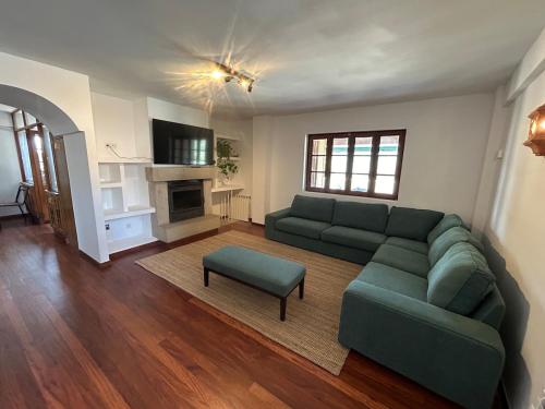 a living room with a green couch and a table at A Fragua de Nicanor in Vilaboa