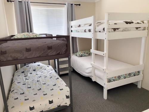 a bedroom with two bunk beds and a bunk ladder at Sea-renity Now in Lancelin
