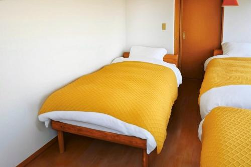 a room with two beds with yellow blankets at Sendai FLAT 01 GORIN in Sendai