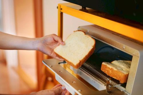 a person holding a piece of bread in an toaster oven at Sendai FLAT 01 GORIN in Sendai