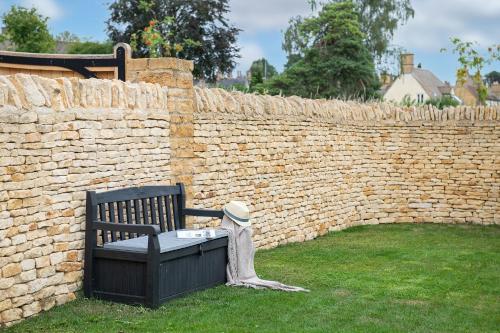 a bench in a yard next to a brick wall at Rowan Cottage-Ebrington in Ebrington