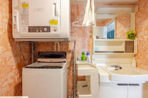 Una pequeña cocina con estufa y fregadero. en Onjjukuオーシャンビューコンドミニアム最上階角部屋, en Onjuku