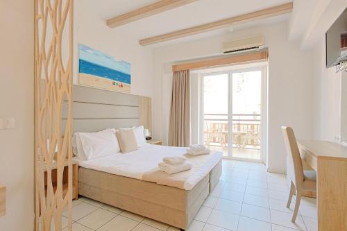 a bedroom with a bed and a desk and a window at Porto Greco Village Beach Hotel in Hersonissos