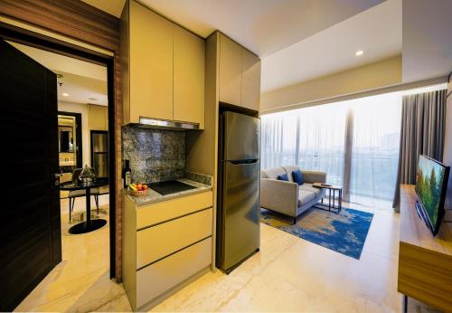 a kitchen with a refrigerator and a living room at Somerset Sudirman Jakarta in Jakarta