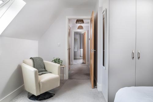 a white room with a chair and a hallway at Rowan Cottage-Ebrington in Ebrington