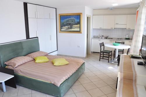 a bedroom with a bed with yellow pillows and a kitchen at Apartments & Rooms Riva in Piran
