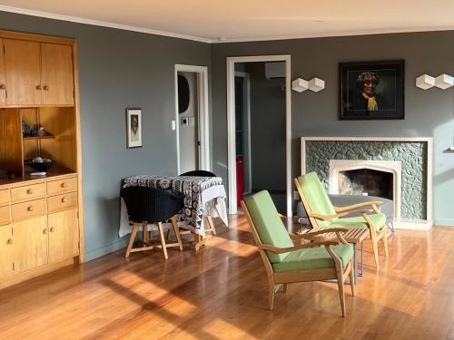 a living room with green chairs and a fireplace at Cashmere Cool in Christchurch