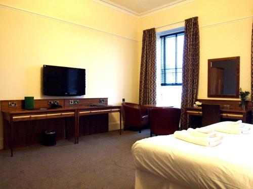 a hotel room with a bed and a flat screen tv at The Bank in Anstruther