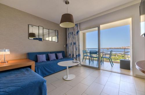 a living room with a blue bed and a table with chairs at Best Western Plus Ajaccio Amirauté in Ajaccio