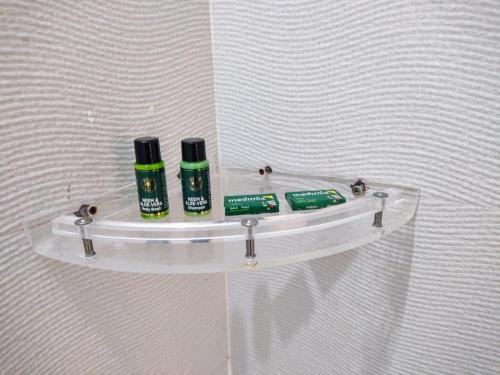 a glass shelf on a wall with two bottles ofodorizers at PIITAMBARA HOMES LUXURY Stay in Faizābād