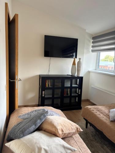 a room with two beds and a tv on the wall at Liepaja Apartments in Liepāja