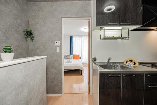 a kitchen with a sink and a room with a bed at 301 6 mins walk from Higashi-Jujo Station Comfortable 1 bedroom apartment on the 3rd floor Direct access to Akihabara and Ueno in Tokyo