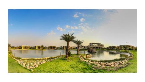 a pond with a palm tree and some houses at Araiya Gir,A Mavintara Resort in Chitrāwal
