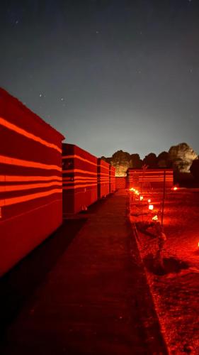 a long red fence next to a field at night at Wadi Rum Magic Camp in Wadi Rum