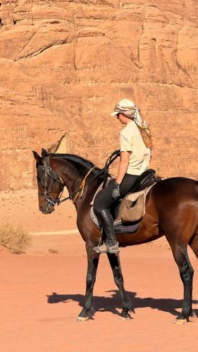 a woman riding a horse in the desert at Wadi Rum Magic Camp in Wadi Rum