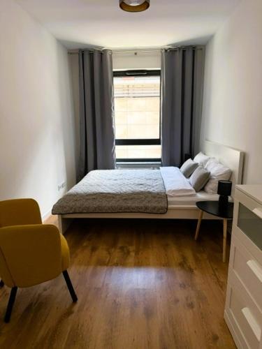 a bedroom with a bed and a window and a chair at Justinrent PALATIUM 12 in Legnica