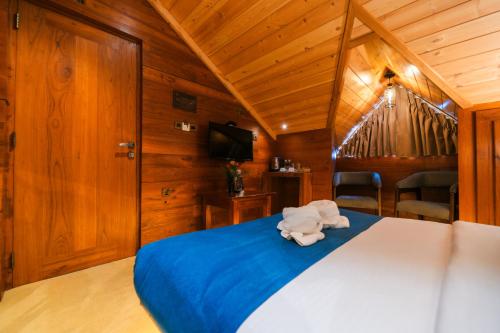 a bedroom with a bed with blue sheets and a tv at Baron Luxury Boutique in Nuwara Eliya
