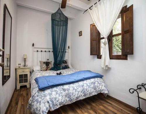 a bedroom with a bed with blue sheets and a window at Casa Rural de Benitandus in Alcudia de Veo