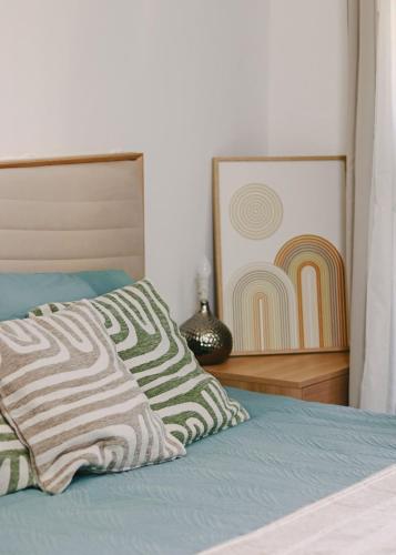 a bed with a pillow and a painting on the wall at Boho Mood - 2 Bedrooms with Terrace & Pool in Sidi Bouqnadel