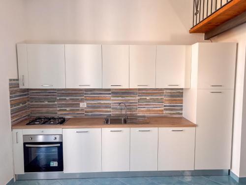 a kitchen with white cabinets and a sink at Il Balcone sul Castello in Ischia